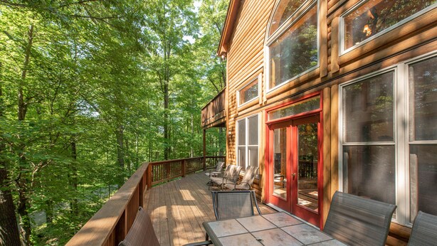 Eine Holzhütte mit einer Terrasse, Sitzgelegenheiten im Freien und großen Fenstern.