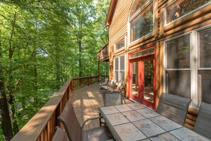 A wooden cabin with a deck, outdoor seating, and large windows. - Spacious Deep Creek Stay w/ Rustic Charm (MCHENRY)