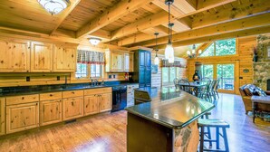 A spacious kitchen with wooden cabinets, a large island, and a stone fireplace. - Dog Friendly Home in Deep Creek Hills w/ Hot Tub (McHenry)