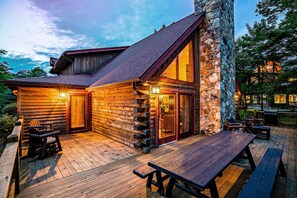 Eine Blockhütte mit Steinofen, Holzterrasse und Sitzgelegenheiten im Freien.