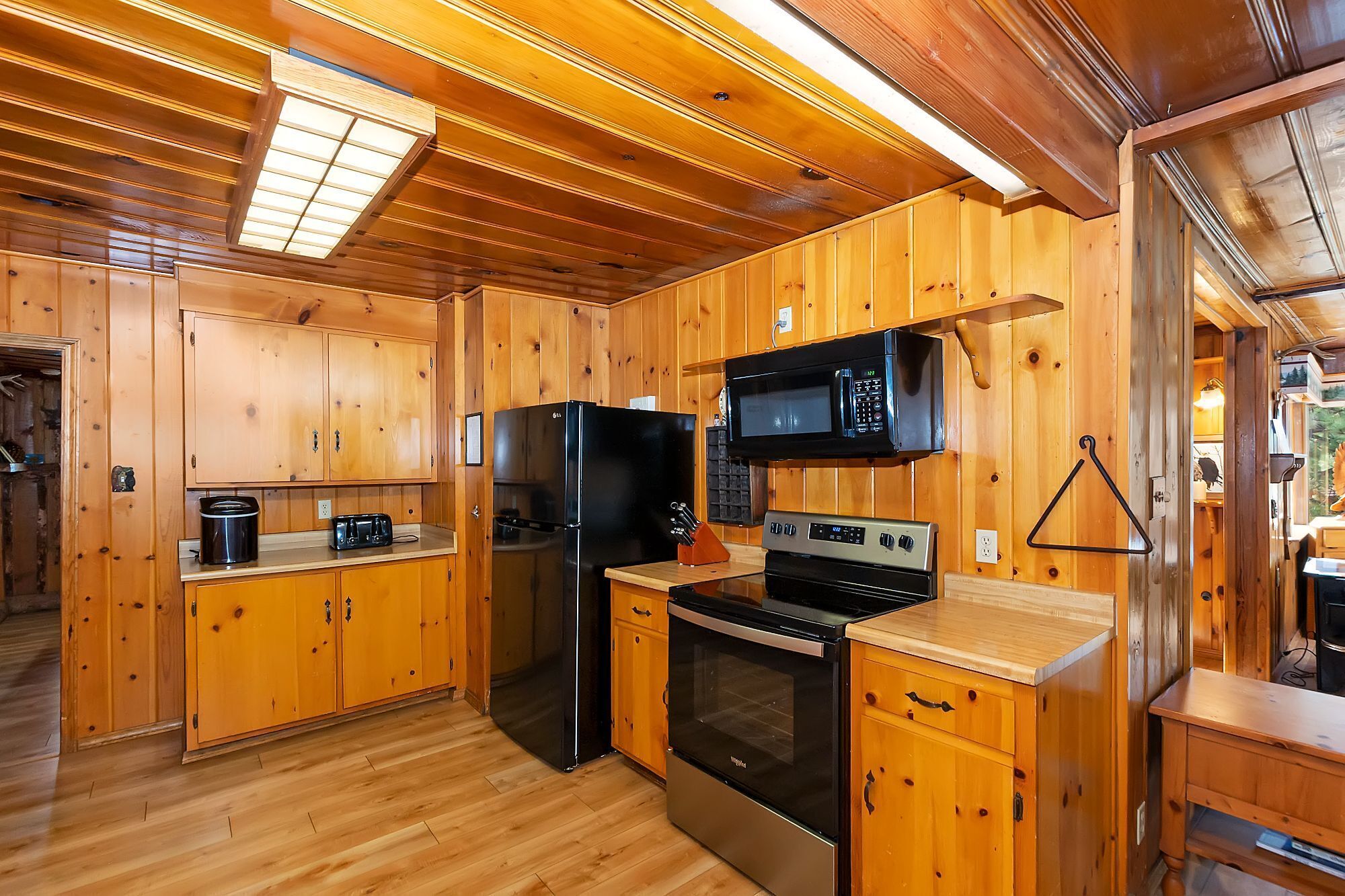 Cocina de cabaña de madera con refrigerador, microondas, estufa y gabinetes de madera.