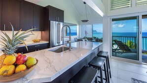 Una cocina moderna con encimera de mármol, electrodomésticos de acero inoxidable y una isla grande con taburetes de bar.