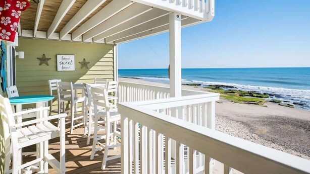A beachside balcony with white chairs and a table, overlooking the ocean. - Ocean Dunes 2119 (Kure Beach)