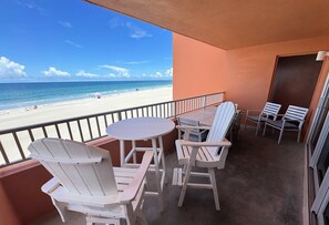 A balcony with a table and chairs, overlooking a beach. - Coquina Beach Club 103 - Anna Maria Island - Condo 2 Bedroom/ 2 Bath ocean view, maximum occupancy of 6 people. (Bradenton Beach)