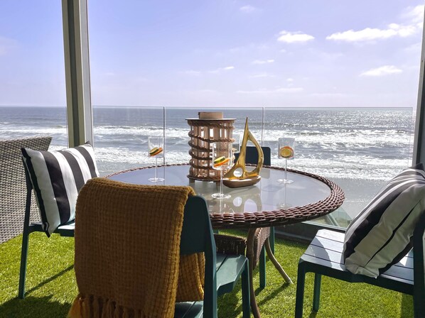 Relax in a serene outdoor space with ocean views, a round table, and comfortable wicker chairs.