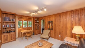 A wooden-paneled room with a wooden table, a chair, a sofa, and a bookshelf. - Luxury Lake Escape in Quiet Cove w/ Dock (Oakland)