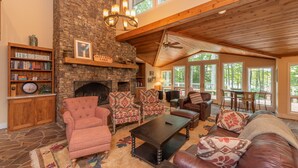 A cozy living room with a stone fireplace, wooden beams, and comfortable seating. - Luxury Lake Escape in Quiet Cove w/ Dock (Oakland)