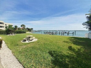 A grassy area with a picnic table and a view of a marina with docks and boats. - Pelican Cove 4 - Anna Maria Island - Condo 2 Bedroom /2 Bath beach side, maximum occupancy of 5 people. (Bradenton Beach)