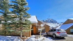 Un paysage enneigé avec un bâtiment en pierre, un arbre et une voiture garée.
