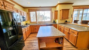 Une cuisine spacieuse avec des meubles en bois, un plan de travail en granit et un grand îlot central.