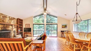 A spacious living room with a fireplace, a television, and a dining area with wooden furniture. - Eric's Landing ~ Riverfront, Fun with Friends Getaway! Dog Friendly! (Guerneville)