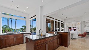 Una cocina moderna con una isla grande, armarios empotrados y vistas a palmeras.