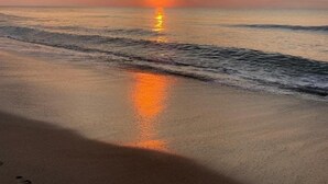 Una playa al atardecer con el sol reflejándose en el agua.