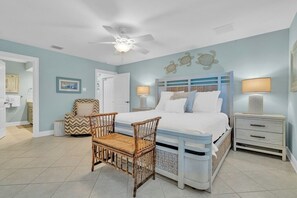 Une chambre à coucher avec un lit, deux tables de chevet, une chaise et un ventilateur de plafond.