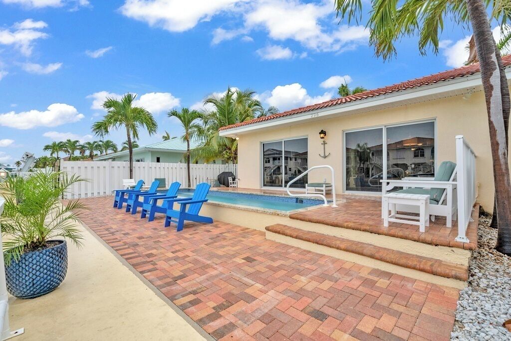 A poolside area with blue chairs, a small pool, and a covered seating area with white chairs.