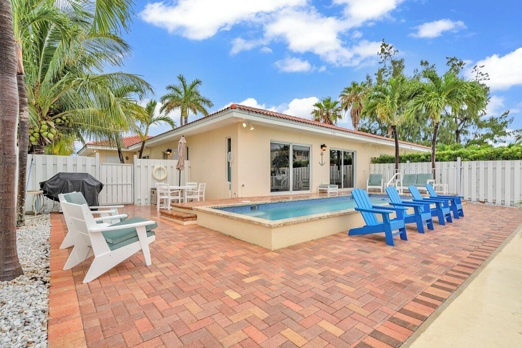 Une maison avec une piscine, un espace salon extérieur et des palmiers.