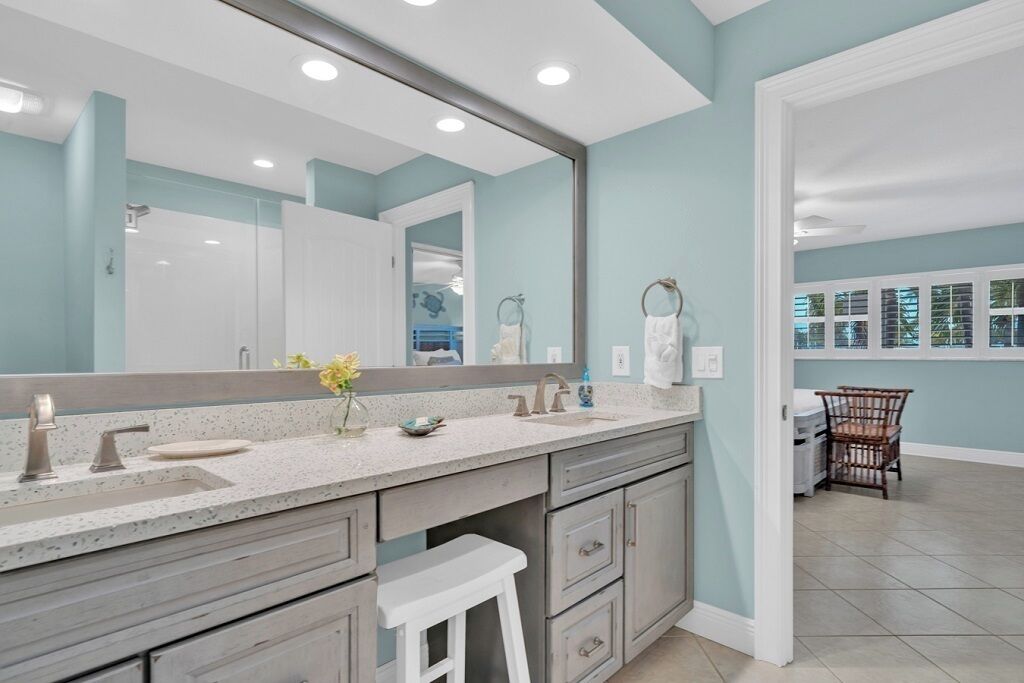 A bathroom with a large mirror, a sink with a faucet, and a vanity with drawers.