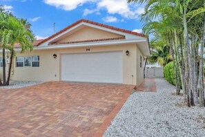Une maison de plain-pied avec une porte de garage blanche, portant le numéro 296, et un toit recouvert de tuiles rouges.