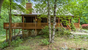 A wooden cabin with a deck, surrounded by trees and a garden. - Spacious Cedar Chalet w/ Hot Tub & Pool Table (Swanton)