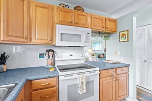 A kitchen with wooden cabinets, a white microwave, a stove, and a sink. - LAST MINUTE DISCOUNT SPECIAL!  New Ductless Split A/C System! (Kailua-Kona)