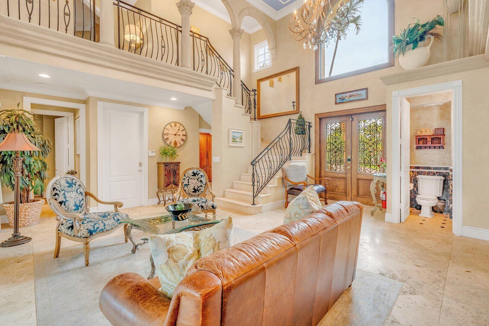 A spacious living room with a high ceiling, a staircase, and a view of the outdoors.