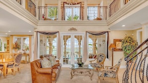 A luxurious interior with a grand staircase, elegant furniture, and large windows offering views of the outdoors. - P05 - 5 bedroom Ocean Front home with Private pool and deep water dockage. (Key Colony Beach)