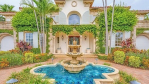 A luxurious building with a central fountain, surrounded by well-maintained gardens and palm trees. - P05 - 5 bedroom Ocean Front home with Private pool and deep water dockage. (Key Colony Beach)