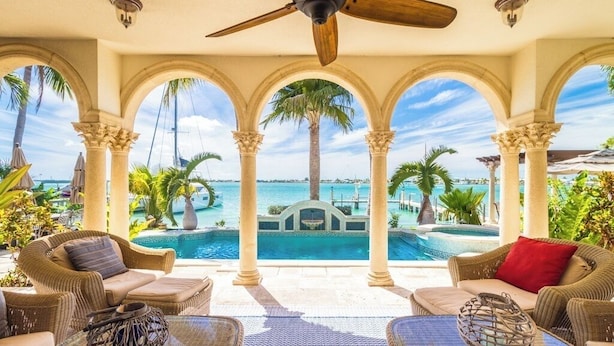 A poolside area with wicker furniture, a ceiling fan, and a view of a pool and palm trees. - P05 - 5 bedroom Ocean Front home with Private pool and deep water dockage. (Key Colony Beach)