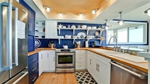 A modern kitchen with stainless steel appliances, white cabinetry, and blue accents.