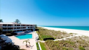 Un hotel con piscina, vistas a la playa y un edificio de dos plantas con balcones.