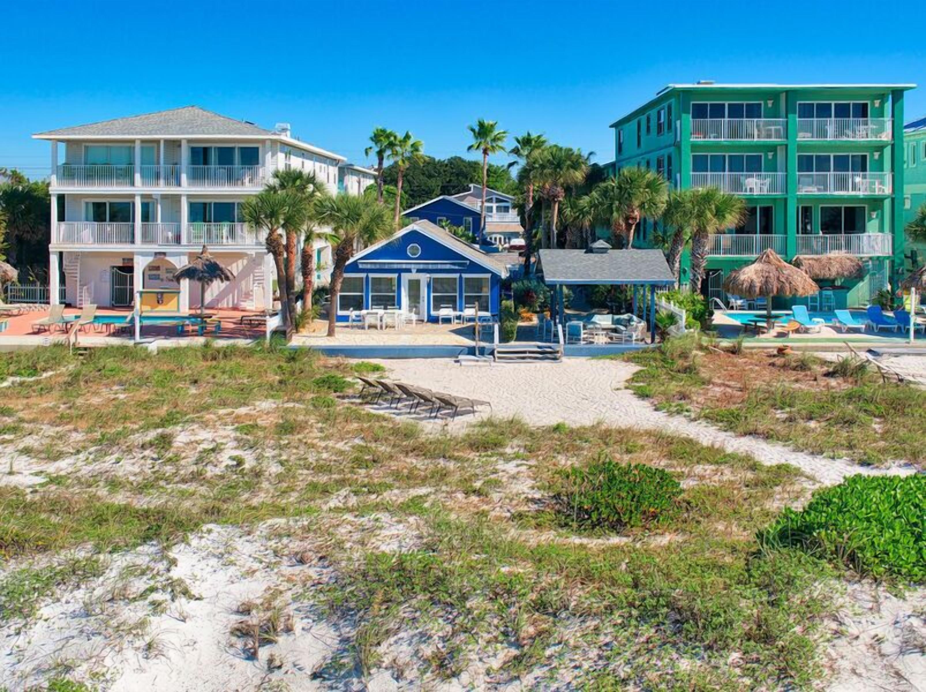 Un h ôtel en bord de mer composé de plusieurs bâtiments, dont une imposante structure bleue abritant une piscine et un espace de détente.