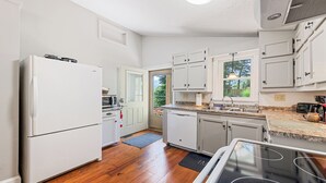 Une cuisine compacte avec des meubles blancs, un four encastré, un four à micro-ondes et un lave-vaisselle.