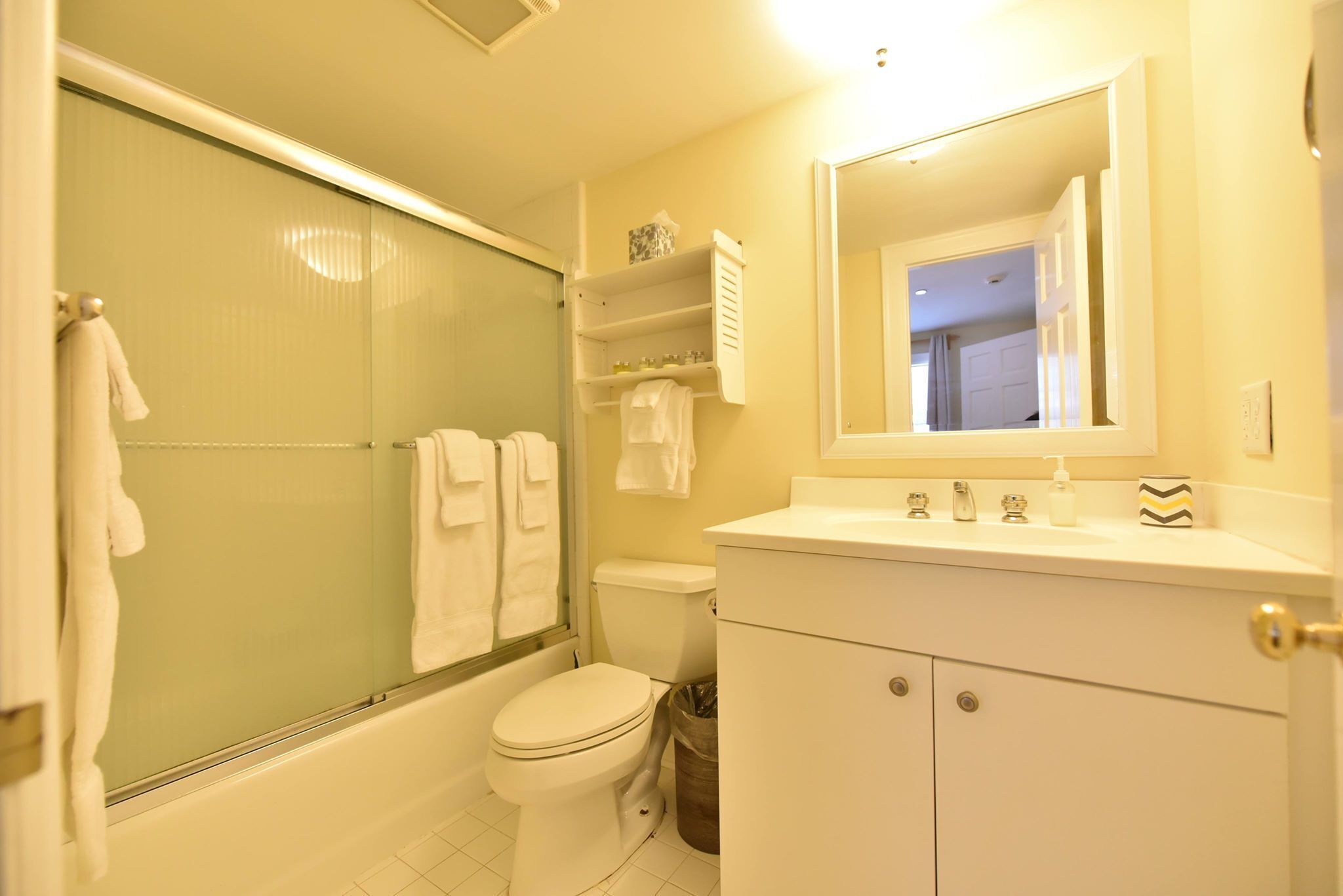 A bathroom with a toilet, a shower, and a sink with a mirror.