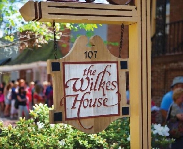 A wooden sign with the text "the Wilkes House" and the number "107" indicating a property or location.