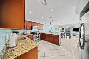 Una cocina moderna con encimeras de granito, electrodomésticos de acero inoxidable y armarios de madera.