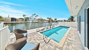 A pool area with a view of a body of water, a white fence, and a building with a balcony. - P22 - Lovely 3 bedroom 2 bath duplex with private pool, dockage and Cabana Club (Key Colony Beach)