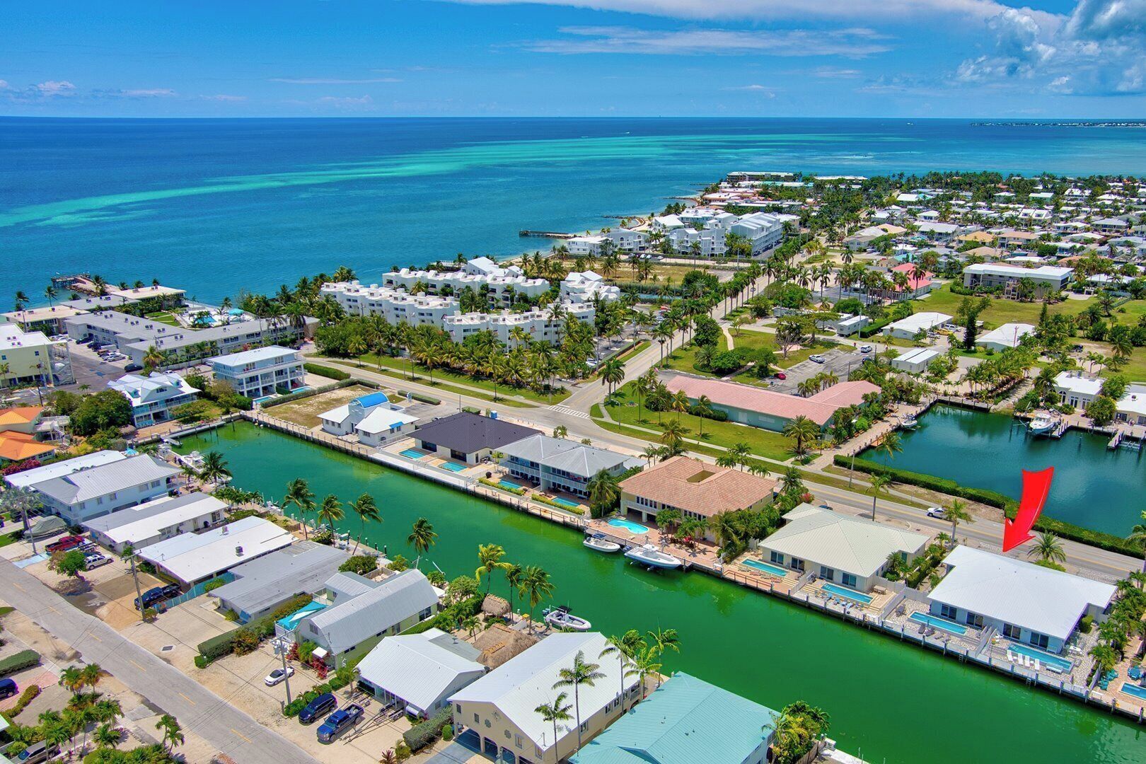 An aerial view of a coastal residential area with houses, a marina, and a large body of water.