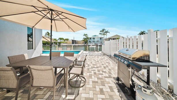 An outdoor patio with a pool, a barbecue grill, and a table with chairs. - P22 - Lovely 3 bedroom 2 bath duplex with private pool, dockage and Cabana Club (Key Colony Beach)