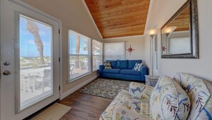 A room with a wooden ceiling, a blue sofa, a floral couch, and a star decoration on the wall.
