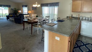 Amplia sala de estar con mesa y sillas de comedor, y una cocina con armarios de madera e isla integrada.