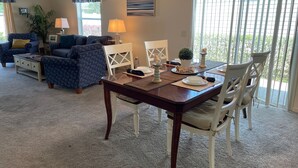 Un comedor con una mesa de madera, sillas blancas y vistas a zonas verdes.