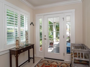 Enter a traditional space with a console table, double doors leading to an outdoor area, and a patterned rug.