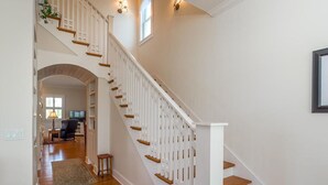 Un escalier avec des rampes blanches et des marches en bois menant à l’étage supérieur.