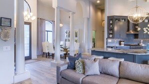 Ein geräumiges Wohnzimmer mit einer großen Couch, einem Essbereich mit Tisch und Stühlen sowie einer Küche mit modernen Geräten und Einbauschränken.