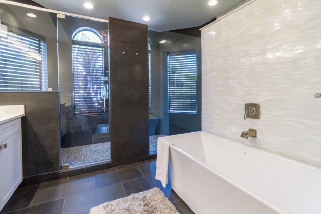 A modern bathroom with a bathtub, a glass shower enclosure, and a large mirror.
