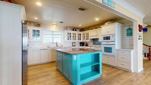 A kitchen with white cabinetry, a turquoise island, and a wooden floor. - A Sea Glass Estate: 9  BR, 5  BA House in Crystal Beach, Sleeps 34 (Bolivar Peninsula)