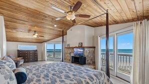 A bedroom with a large bed, a ceiling fan, a television, and a view of the ocean through large windows. - 🏖️LaKaSa House on Hill Street-Oceanfront Home with Gorgeous Views🏖️ (New Smyrna Beach)