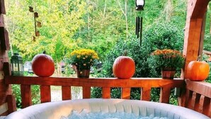 A green inflatable hot tub with a Coleman logo, surrounded by a wooden deck and potted plants.
