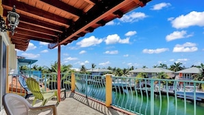A balcony with a view of a marina, a covered area with chairs, and a railing. - P21  - Charming 3 bedroom 3.5 bath duplex with dockage and Cabana Club. (Key Colony Beach)
