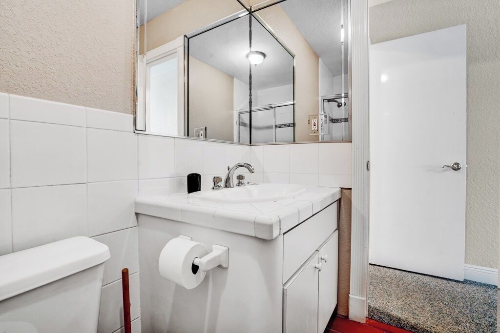 A bathroom with a white sink, a toilet, and a mirror above the sink.